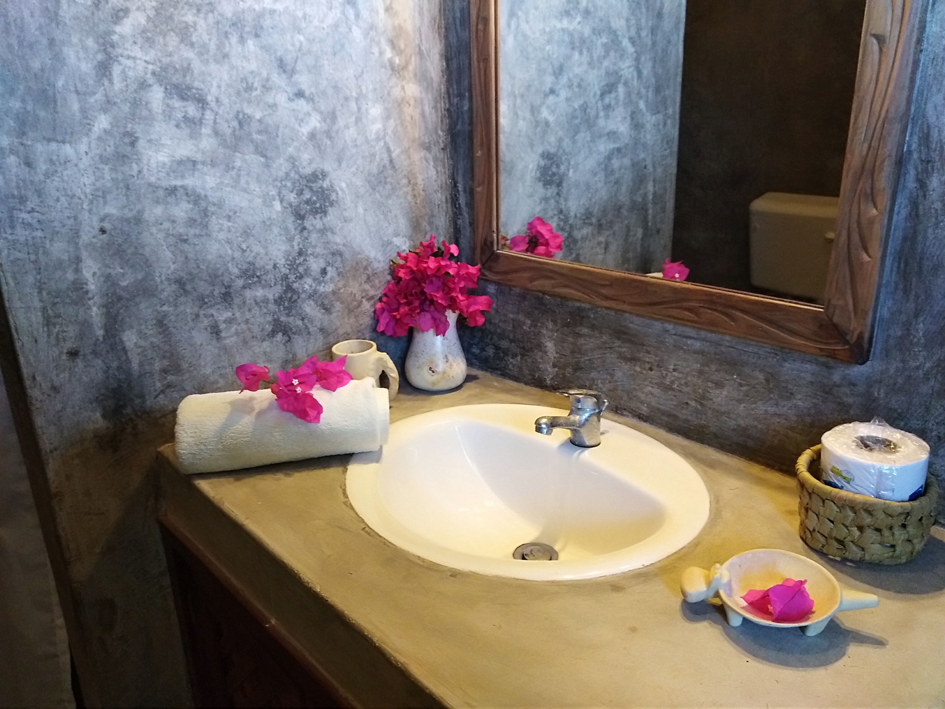 A bathroom with a white sink, a mirror, and a towel with pink flowers.