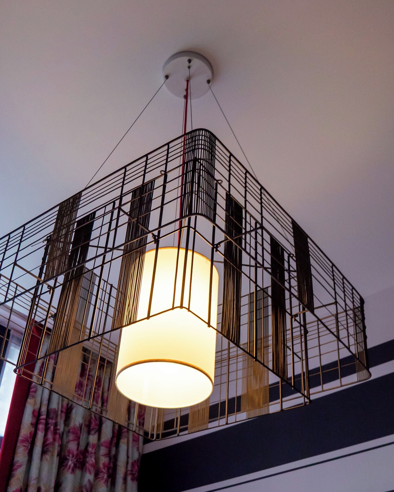 A modern interior with a geometric metal railing structure and a central hanging light fixture.