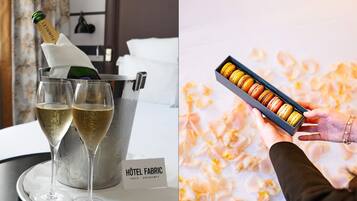 Una botella de champán en un cubo, dos copas de champán, una caja de macarons y un cartel con 'Hôtel Fabric' sobre una mesa.