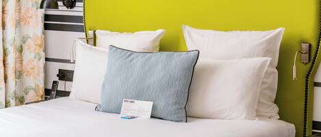 A hotel room with a bed, a nightstand, a telephone, and a wall with horizontal stripes.