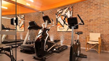 Uma academia com equipamentos de ginástica, parede de tijolos e um espelho grande.