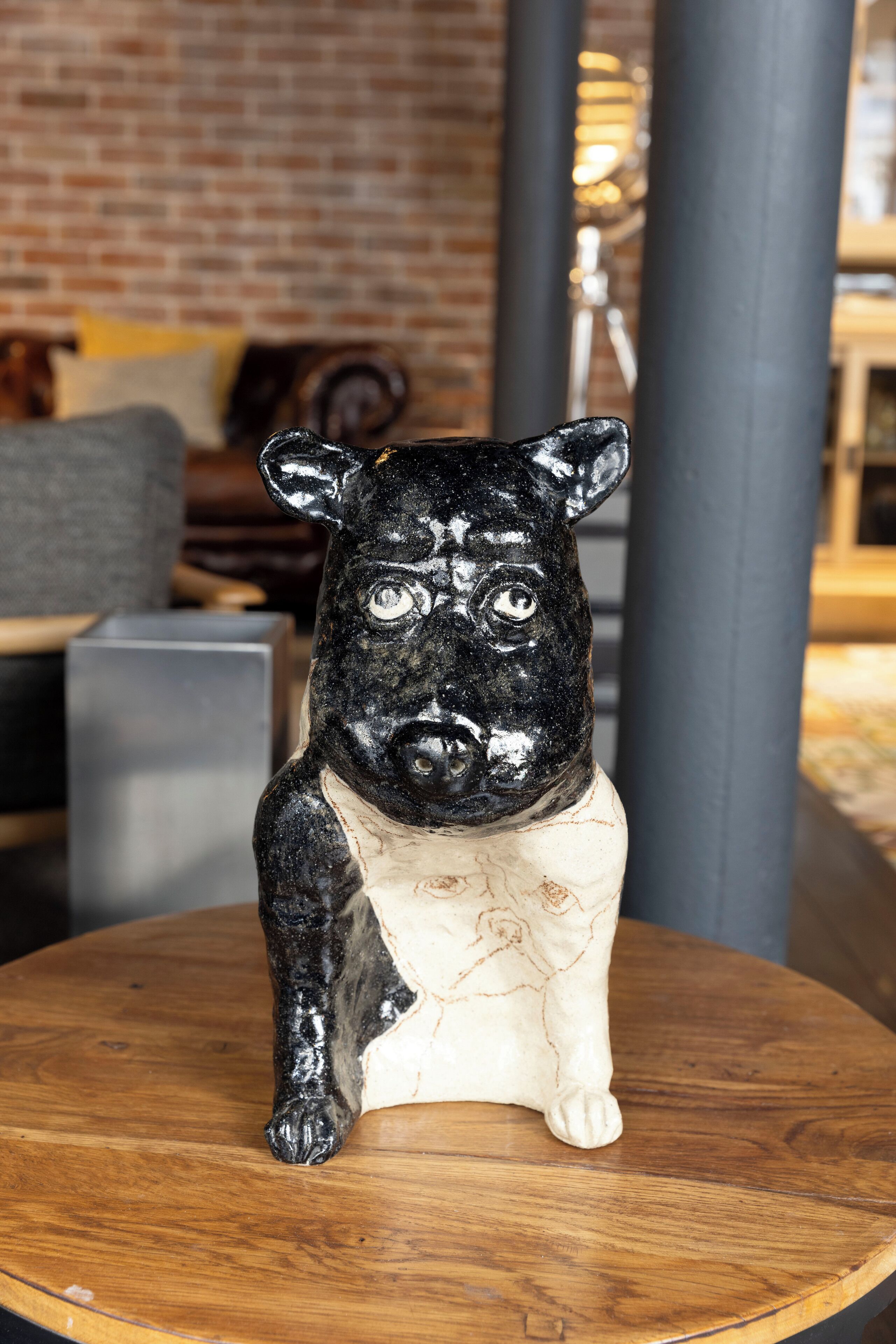 Una figurita de cerdo blanco y negro sobre una mesa de madera redonda.