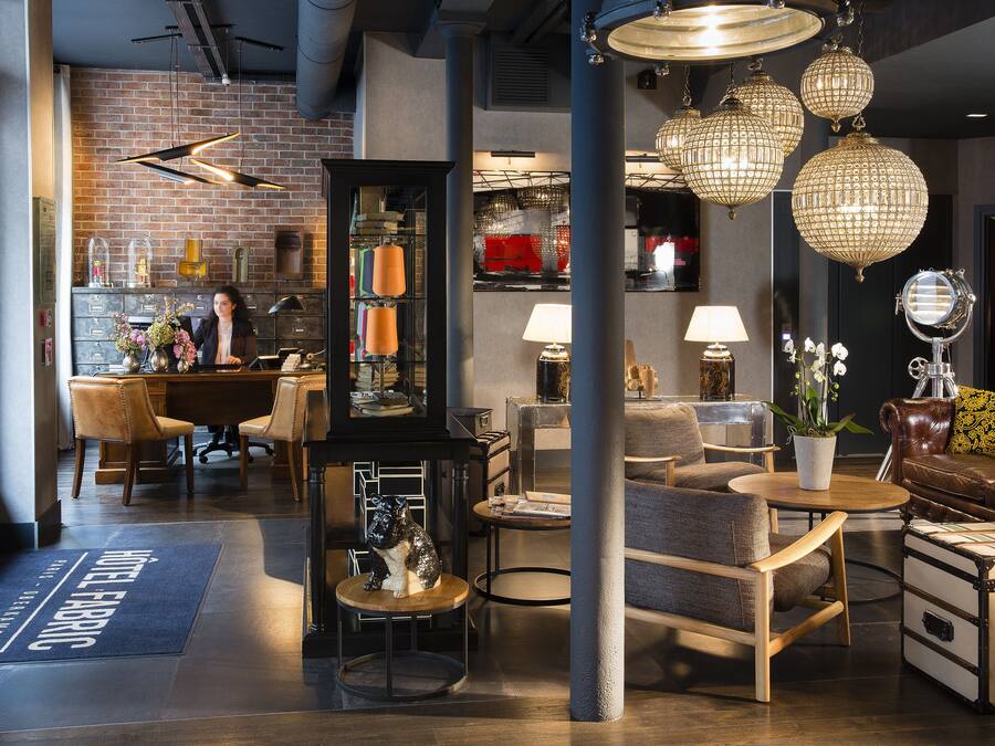 Un moderno vestíbulo de hotel con zona de bar, asientos y un espejo grande.