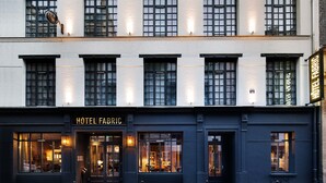 Um edifício de dois andares com uma placa que diz 'HOTEL FABRIC'.