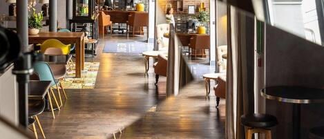 Una cafetería moderna con pared de ladrillo, suelo de madera y diferentes opciones de asientos, incluyendo mesas y sillas.