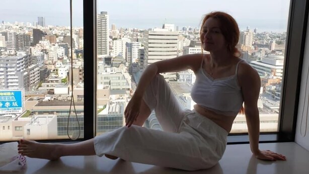 Una persona seduta vicino a una grande finestra con vista sulla città.