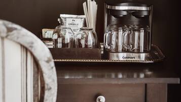 A kitchen counter with a coffee machine, a jar labeled "UMBRIA," and a tray with glassware.
