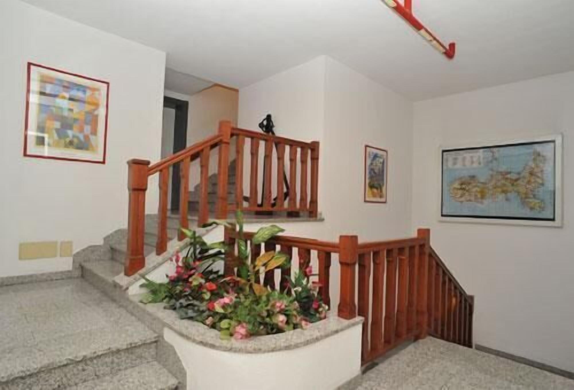Eine Treppe mit Holzhandläufen, einem Blumenbeet und zwei gerahmten Kunstwerken an den Wänden.