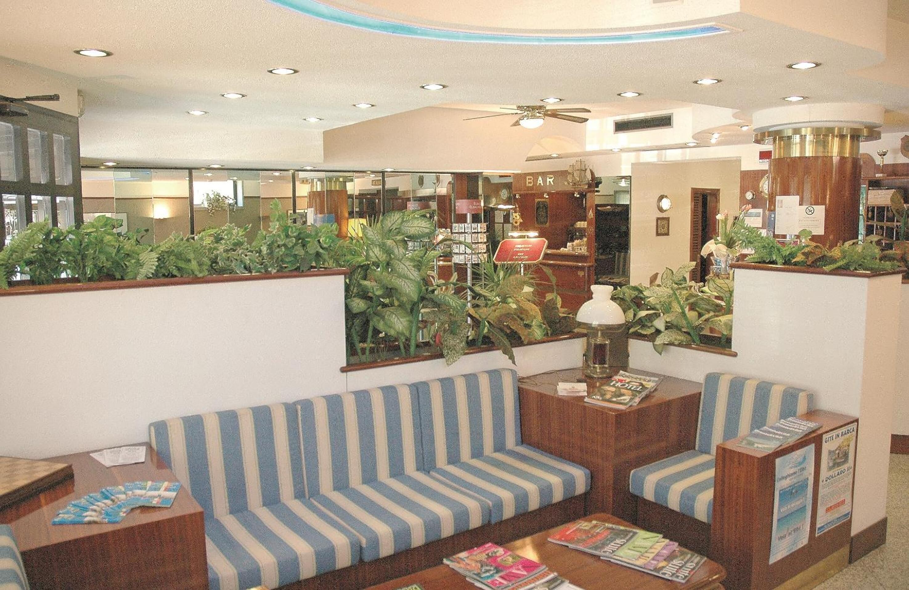 A lobby with striped sofas, a bar area, and various plants.