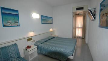 A bedroom with a bed, bedside table, and a chair. There are two wall-mounted lights and a ceiling fan.