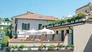 A hotel with a terrace featuring white umbrellas and potted plants. - Hotel Crystal & Residence (Portoferraio)