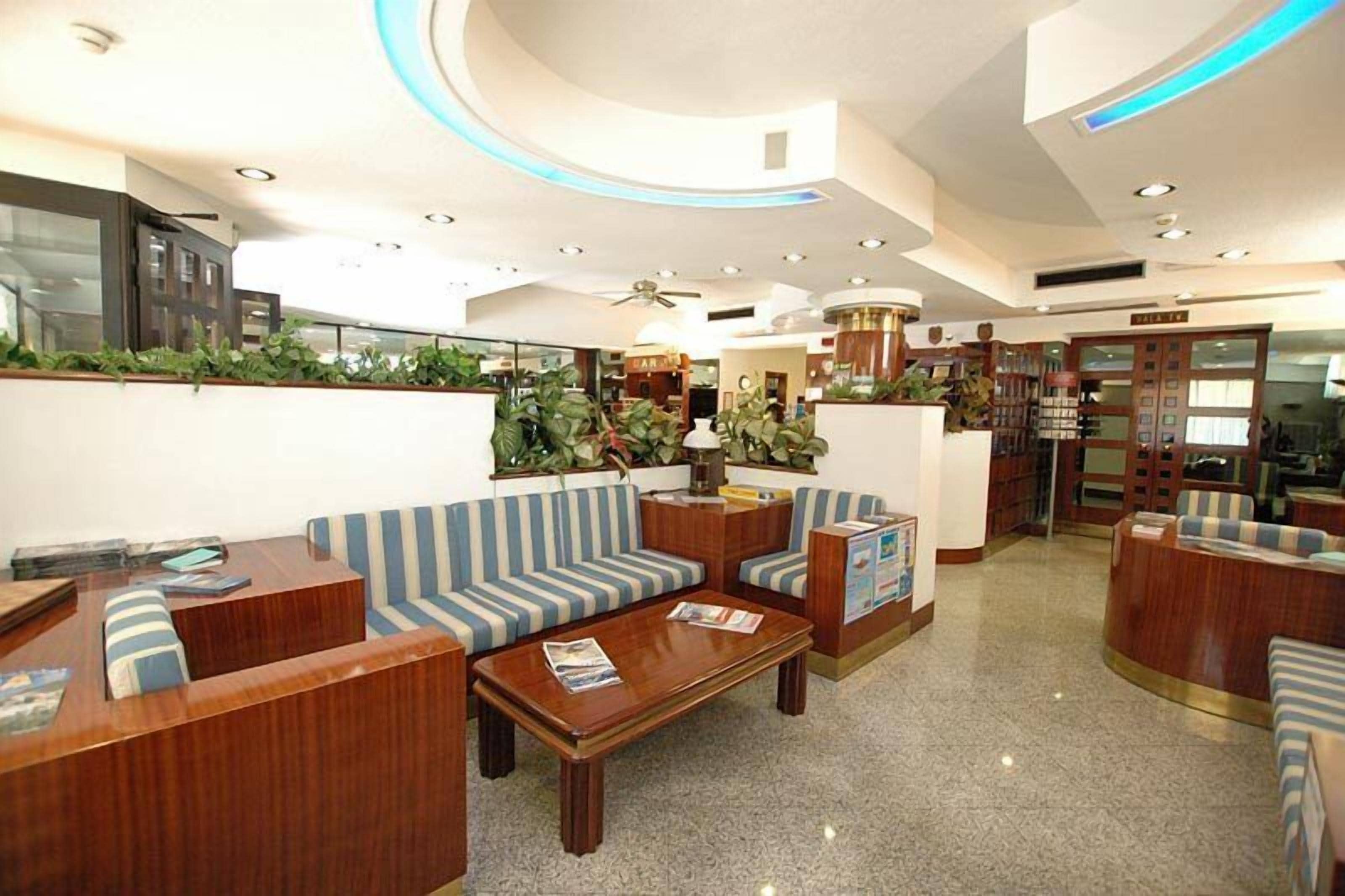 Eine Lobby mit gewölbter Decke, einer Rezeption, gestreiften Sofas und einem Couchtisch.