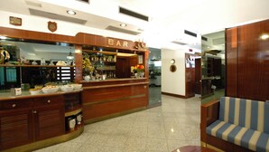 A bar area with wooden cabinets and a counter displaying various bottles and glasses. - Hotel Crystal & Residence (Portoferraio)