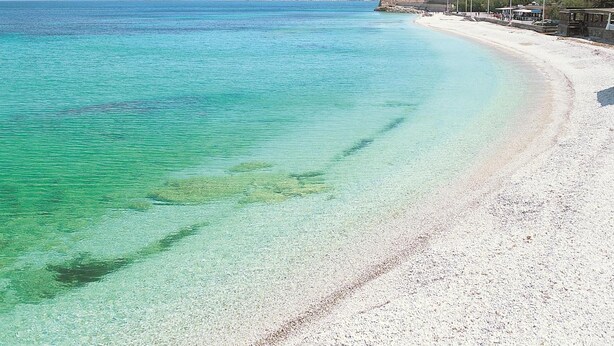 A beach with clear turquoise water, a sandy shore, and a mountainous backdrop. - Hotel Crystal & Residence (Portoferraio)