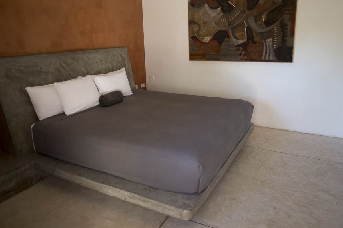 Un dormitorio moderno con cama, almohadas y un cuadro en la pared.