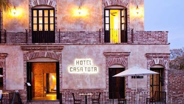 Et hotel kaldet "CASA TOTA" med murstensfacade, flere vinduer og udendørs siddepladser.