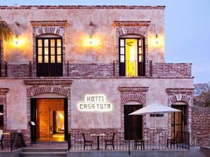 Un hôtel appelé « CASA TOTA », caractérisé par son architecture en briques, ses nombreuses fenêtres et ses espaces de détente en plein air.