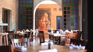 En restaurant med murstensvægge, træborde og stole.