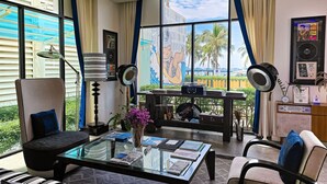 A modern hotel room with a large window, a glass coffee table with magazines, a comfortable sofa, and a decorative vase. - Wave Hotel Pattaya (Pattaya)