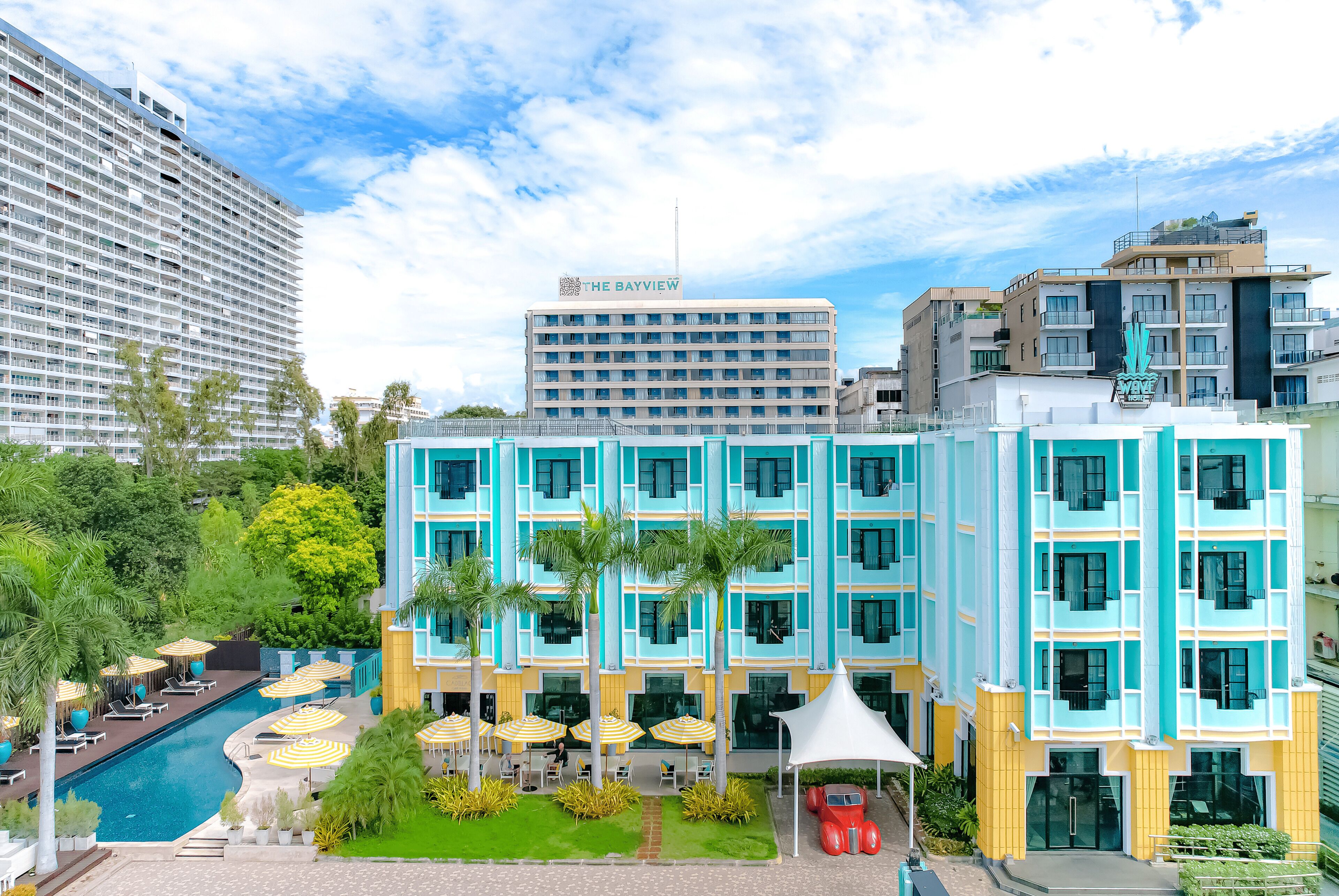 A hotel with a pool, outdoor seating, and a view of surrounding buildings.
