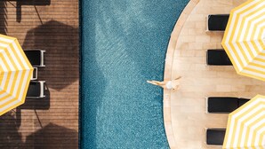 A top-down view of a swimming pool with lounge chairs and yellow striped umbrellas. - Wave Hotel Pattaya (Pattaya)
