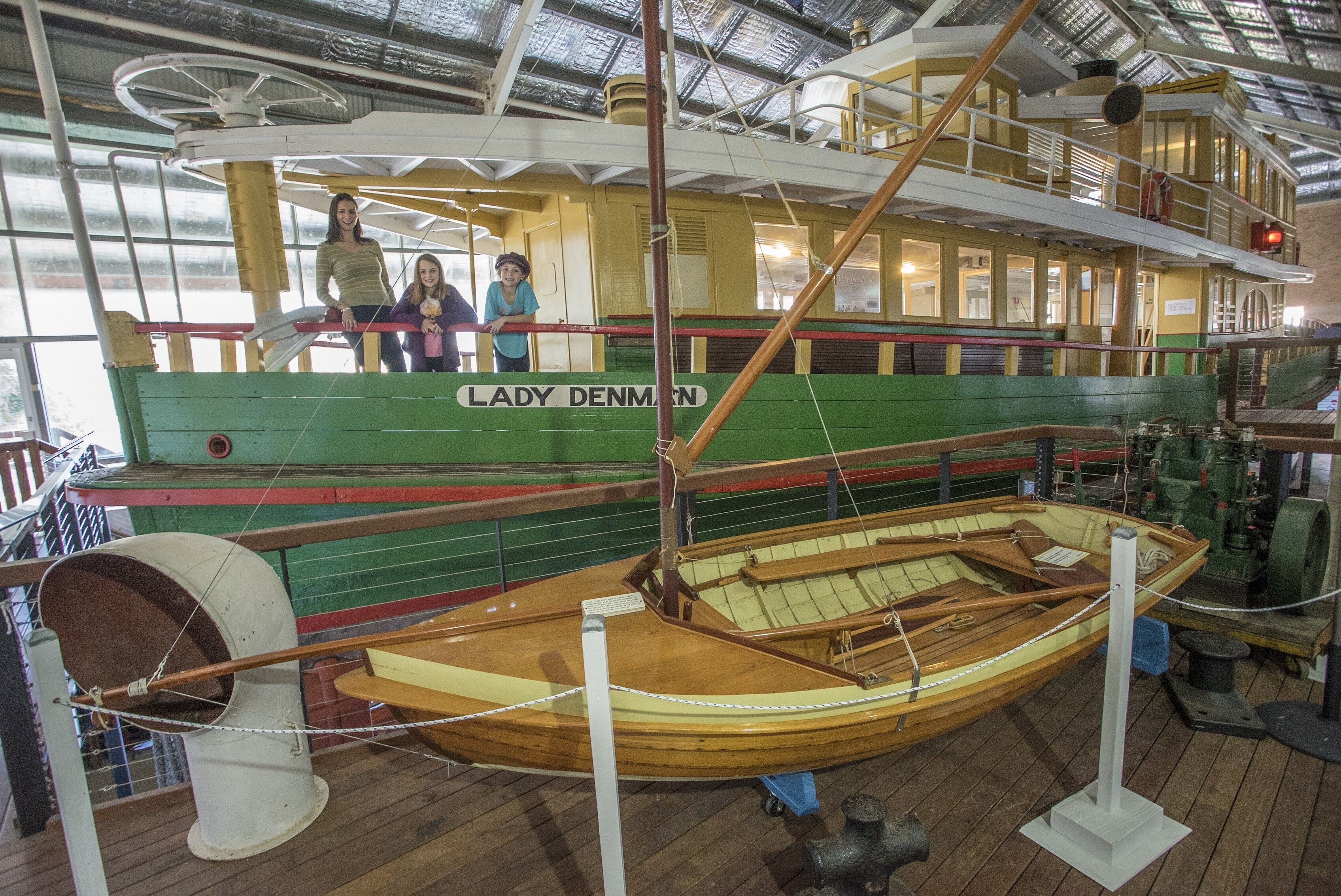 A historic boat named "Lady Denmark" on display, featuring a wooden interior and a green exterior.