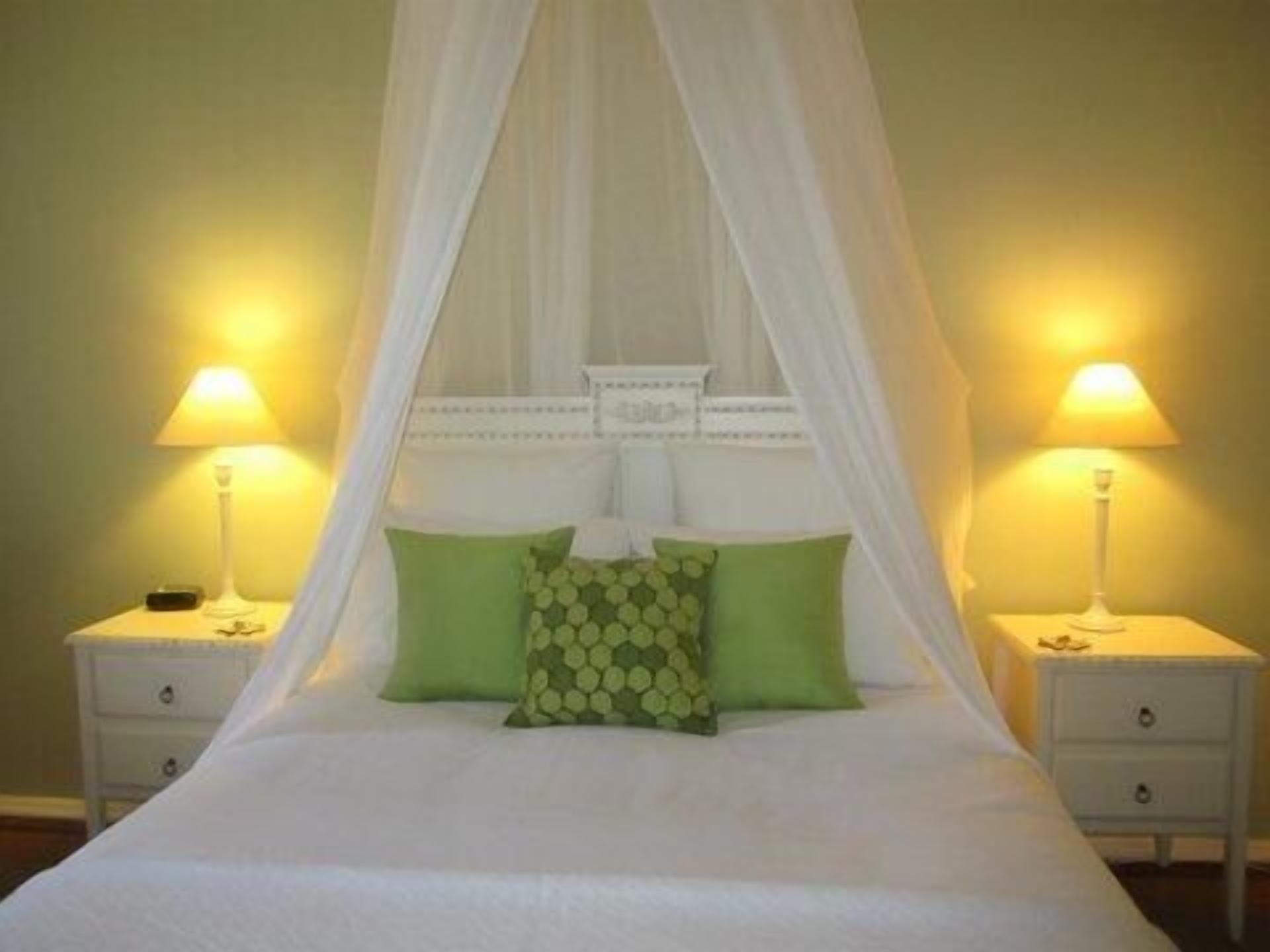 Una cama con dosel, dos mesitas de noche y dos lámparas.