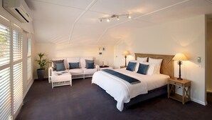 A spacious bedroom with a large bed, two bedside tables, a sofa, and a potted plant. - Plantation House (Rye)
