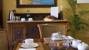 A dining area with a wooden table set for breakfast, including a teapot, cups, and a fruit plate. - Plantation House (Rye)
