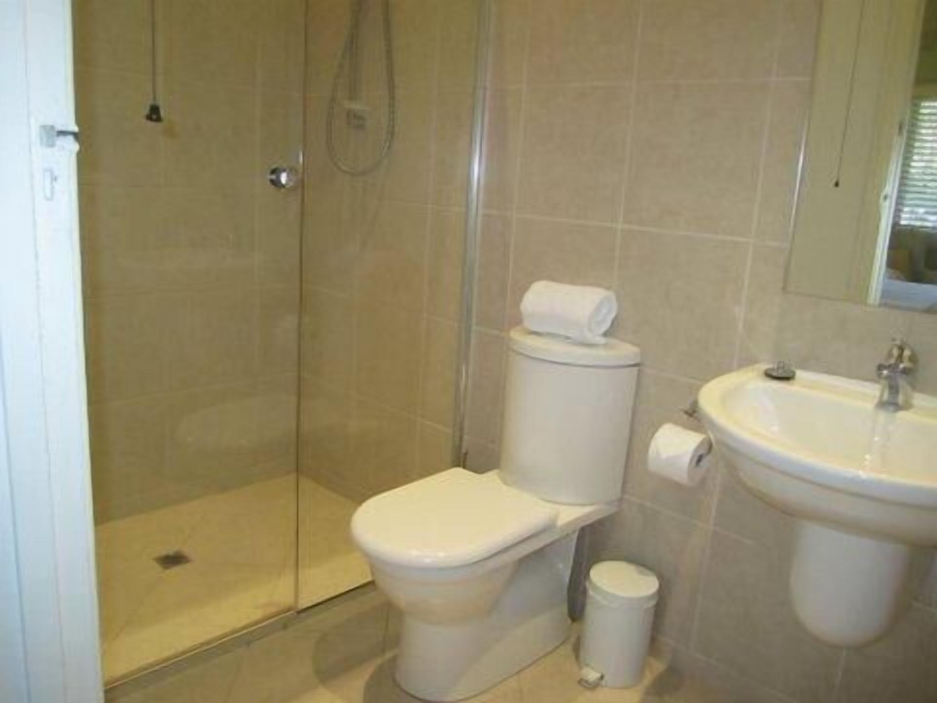 Une salle de bain avec des toilettes, un lavabo et une douche.