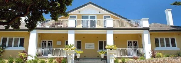 A two-story building with a balcony, columns, and potted plants. - Plantation House (Rye)