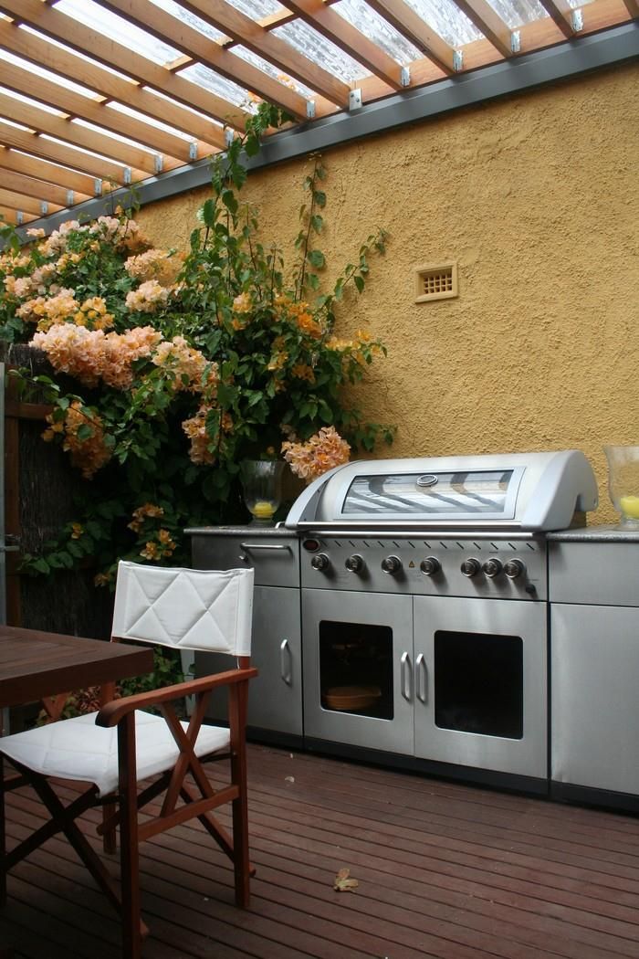 Cuina exterior amb una barbacoa, una taula i una cadira.