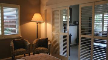 A bedroom with a bed, two chairs, a lamp, and a sliding door leading to a bathroom.