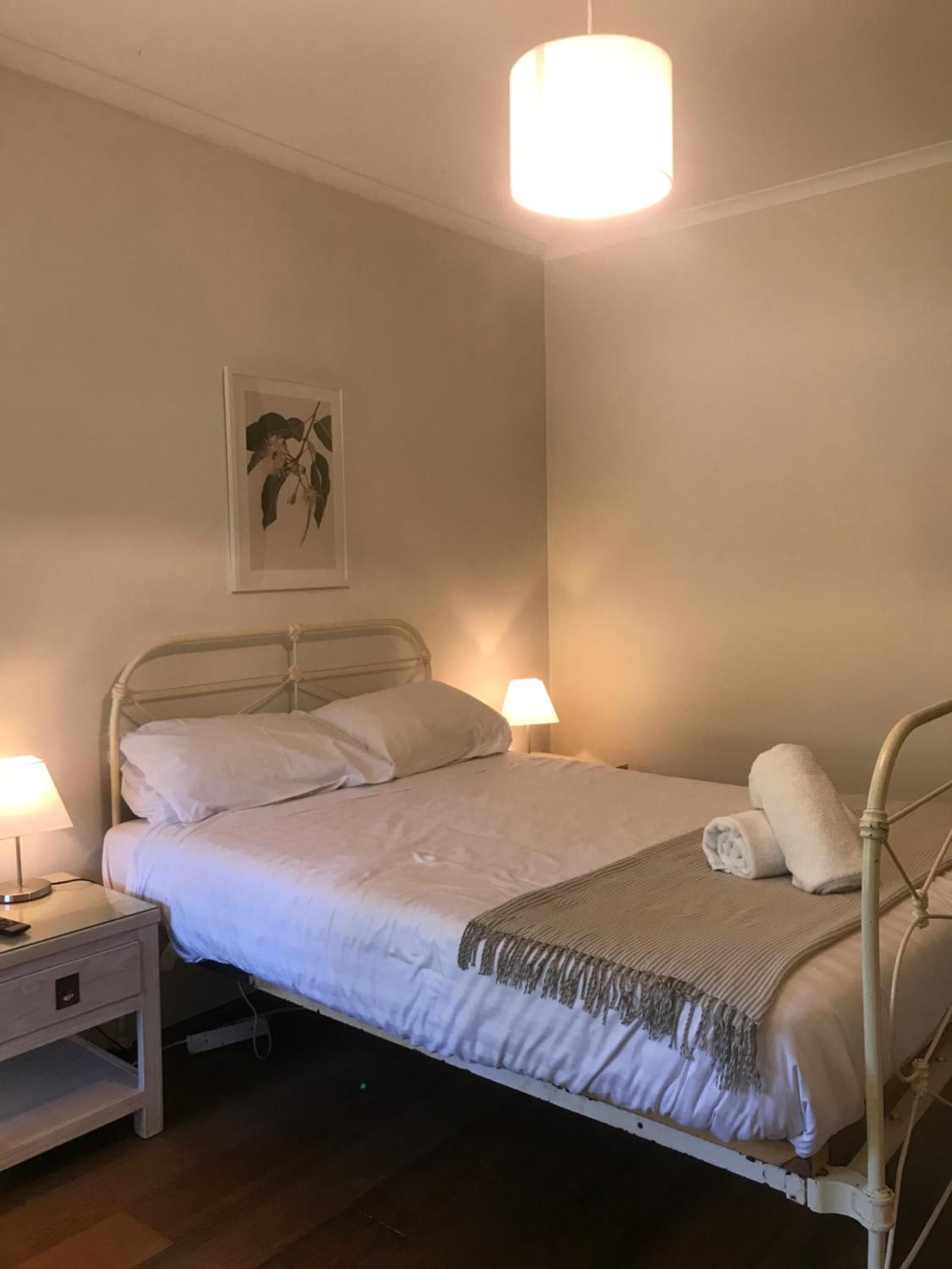 A neatly made bed with white linens, a bedside lamp, and a bedside table.