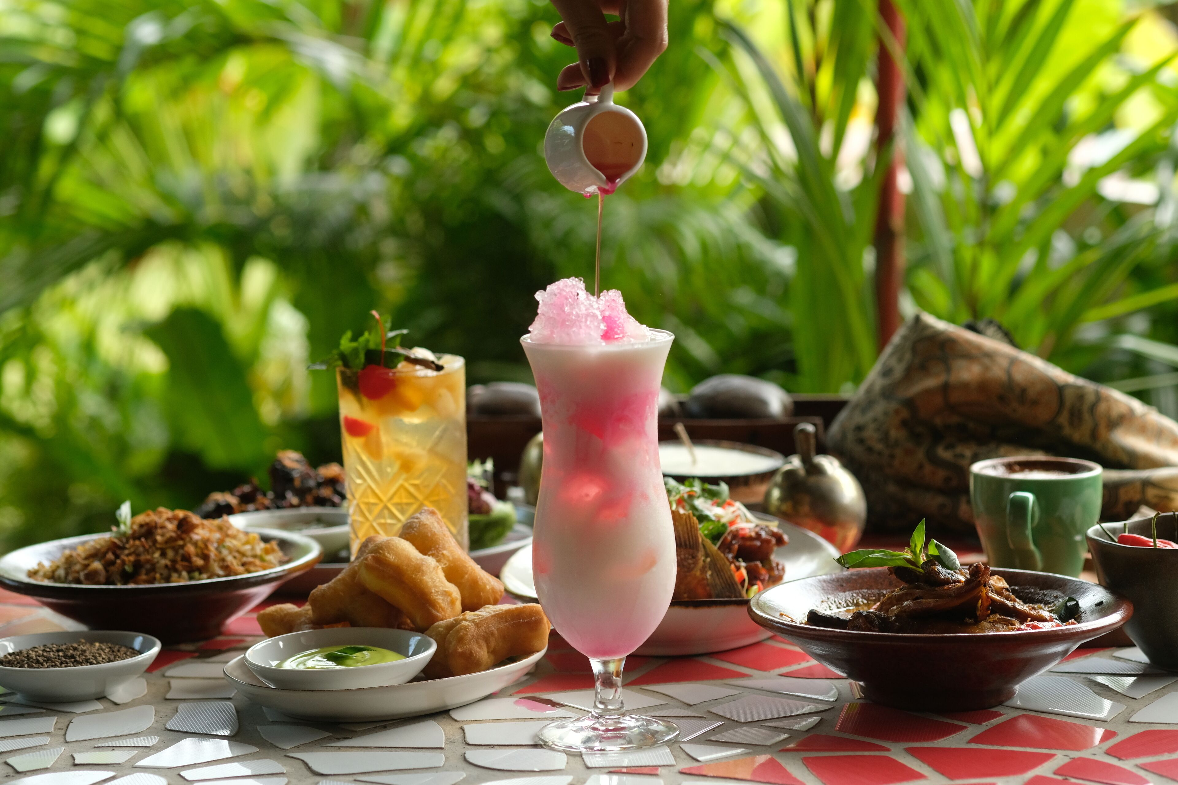 A table with various dishes and a drink being poured.