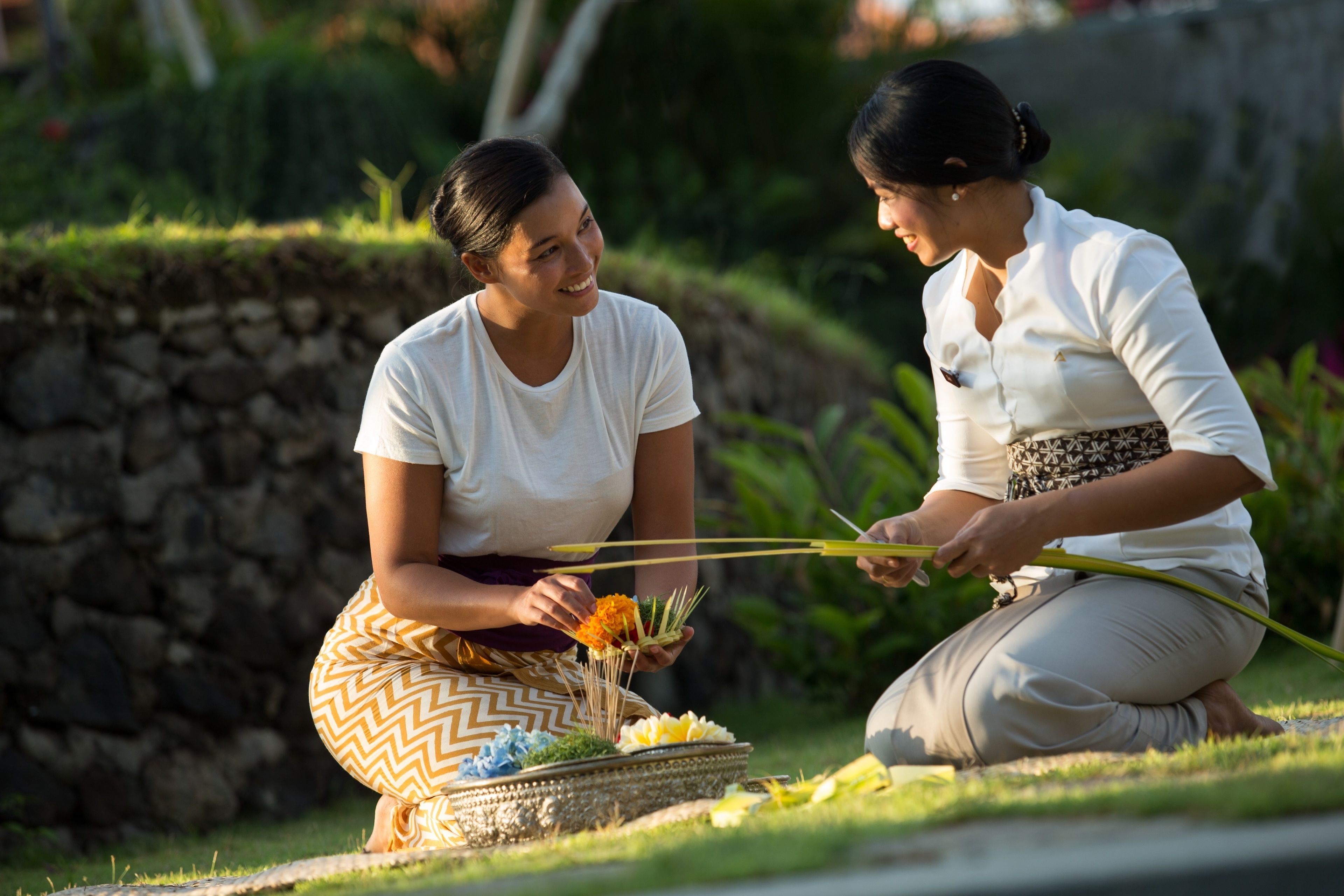Two individuals kneeling on grass, holding offerings.