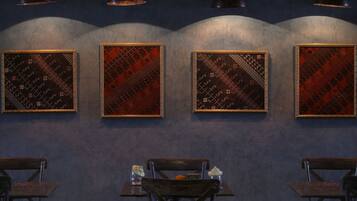 A restaurant interior with four framed wall art pieces, wooden tables, and hanging pendant lights.