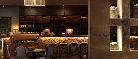 A bar area with a counter, bar stools, and hanging pendant lights.