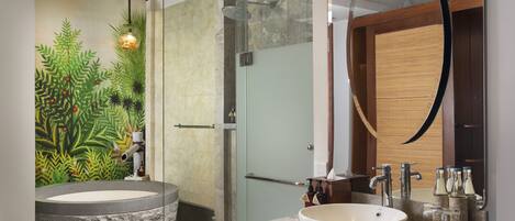 A modern bathroom with a stone sink, a glass-enclosed shower, and a large mirror.