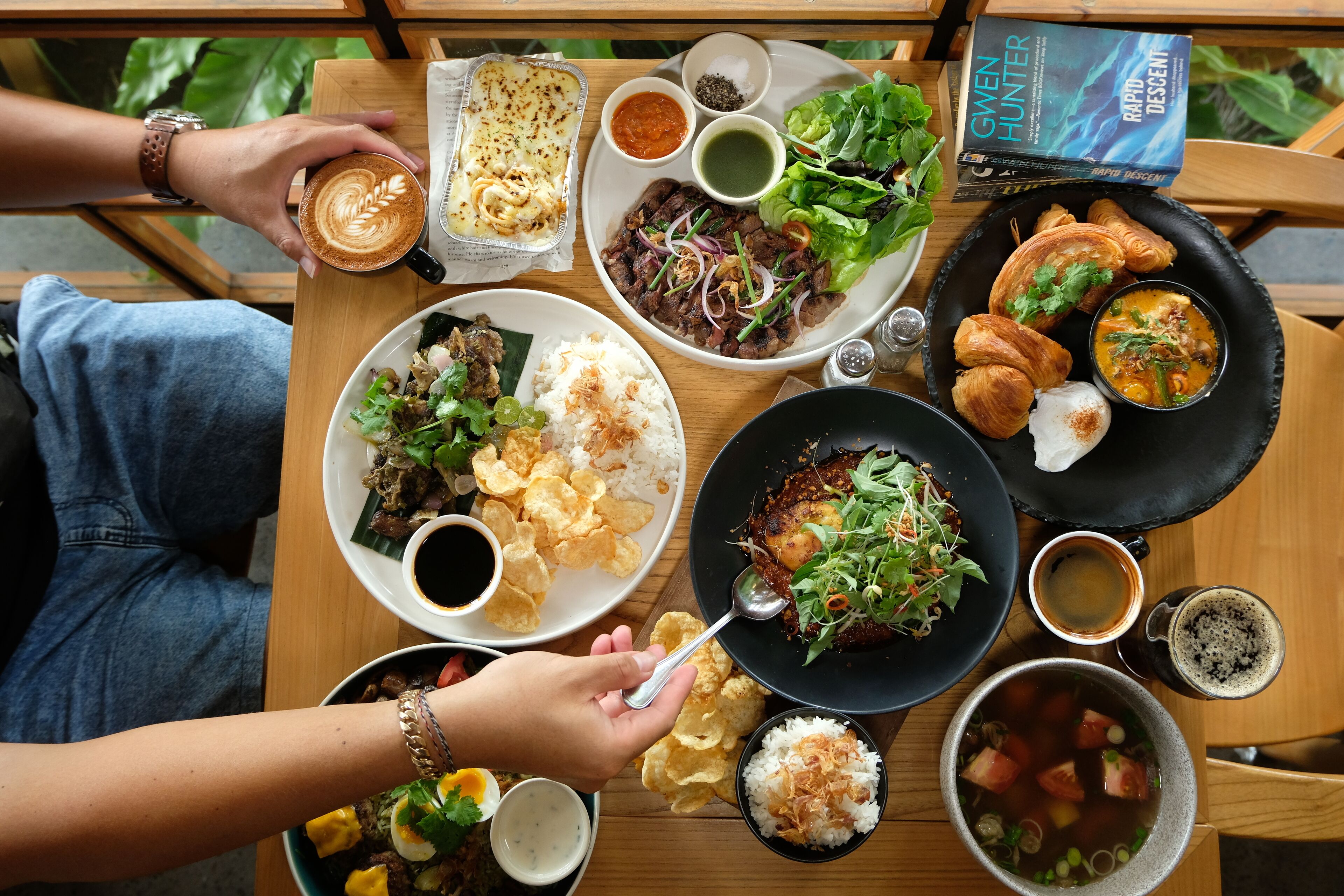 Una mesa con diversos platos que incluyen arroz, carne y verduras, además de bebidas y salsas.
