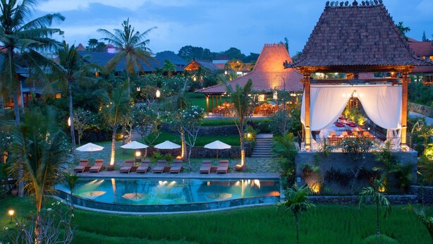 Un resort con piscina, sillas de descanso y una zona de comedor cubierta.