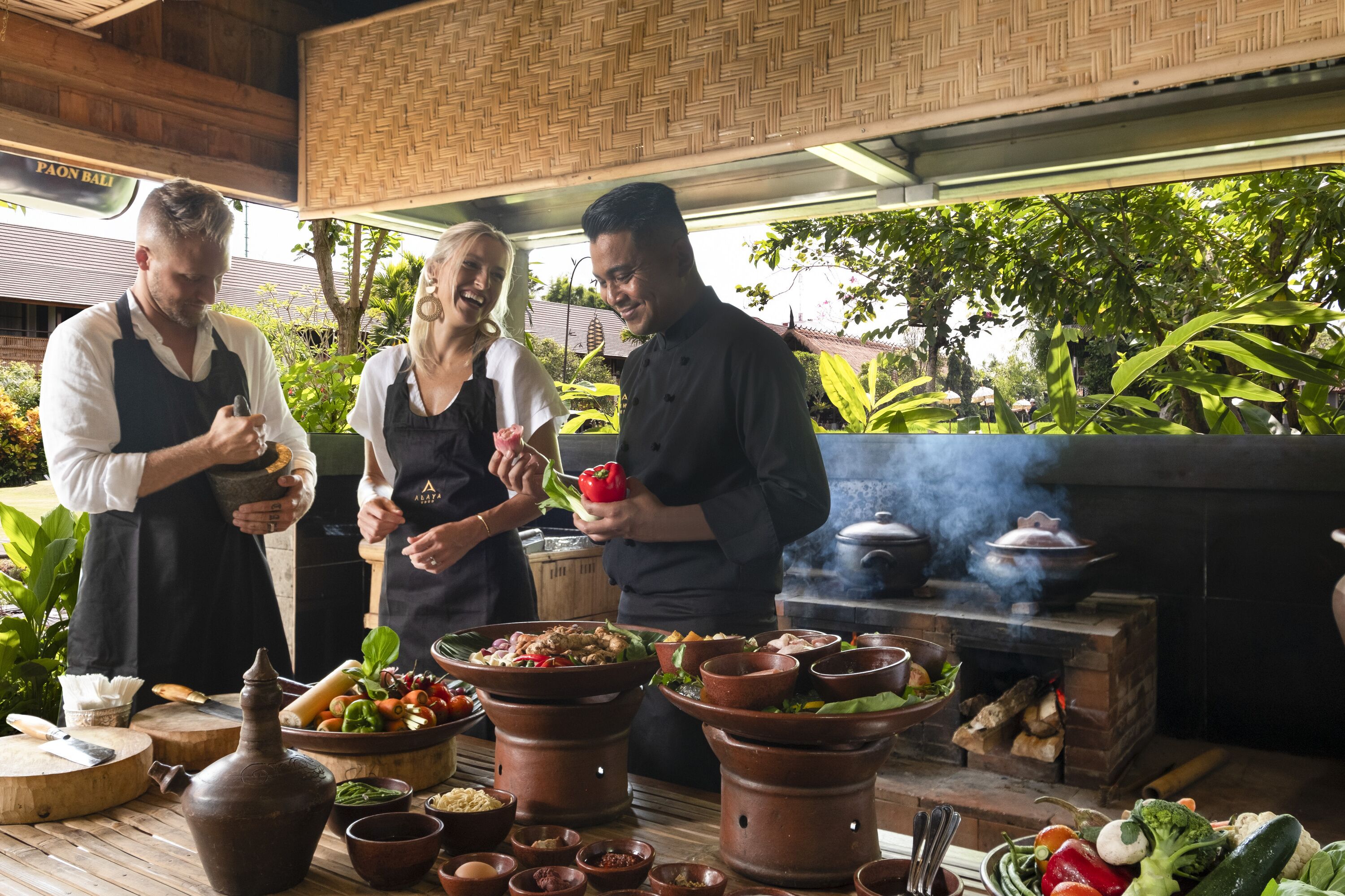 A chef preparing food outdoors with terracotta pots and fresh vegetables.