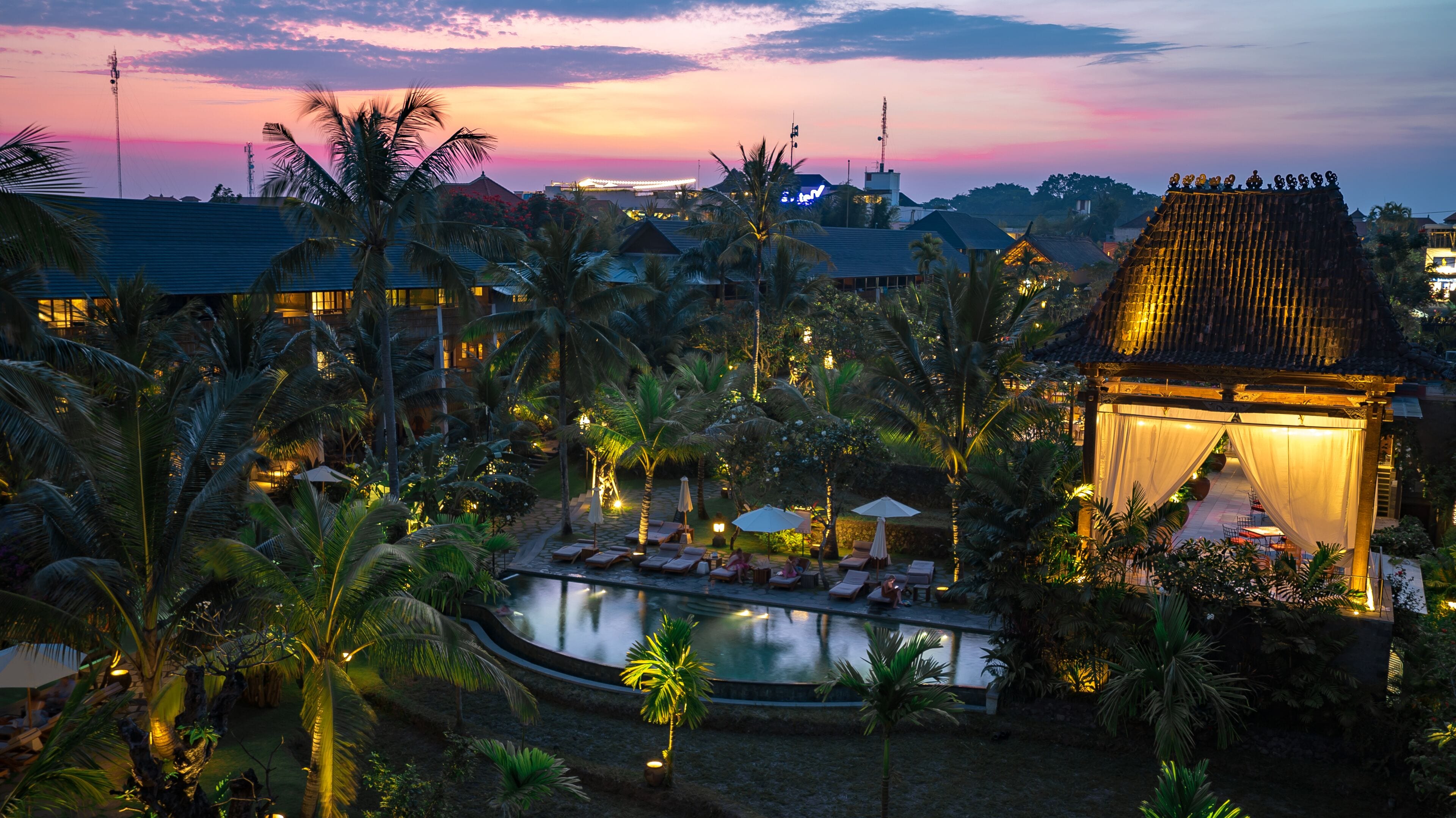 A resort with a swimming pool, palm trees, and traditional architecture.