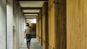 A corridor with bamboo walls and a person carrying a basket.