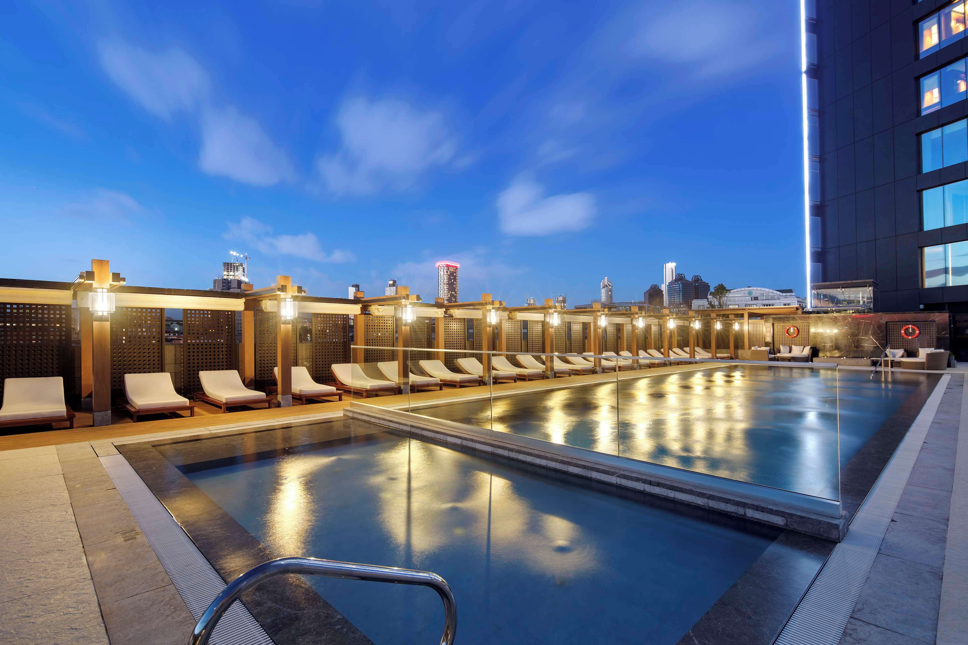 A pool area with lounge chairs and a cityscape view.