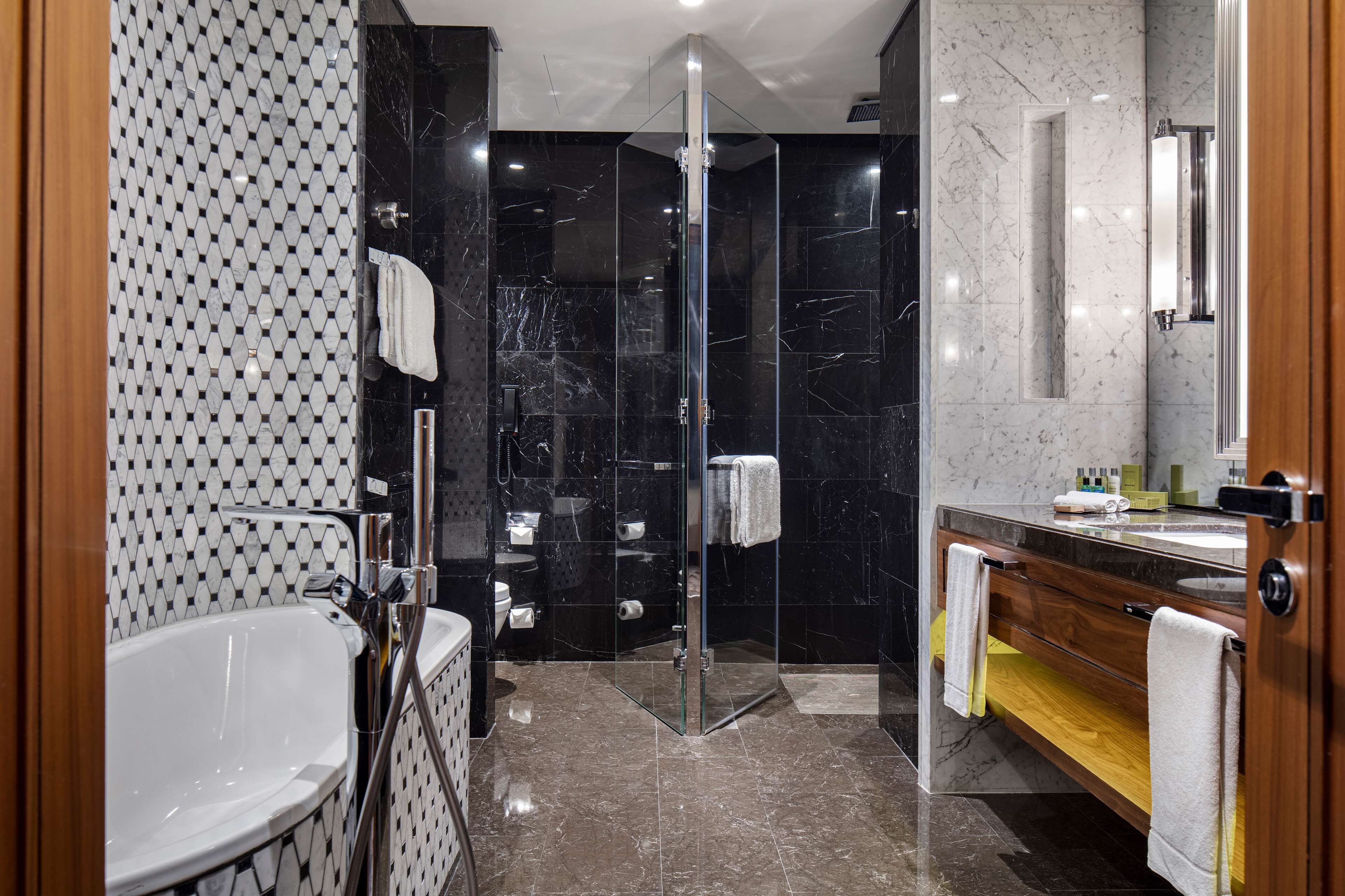 A modern bathroom with a glass-enclosed shower, a freestanding bathtub, and a vanity with a mirror.