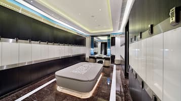 A modern hotel restroom with a long row of lockers, a central bench, and a vanity area.