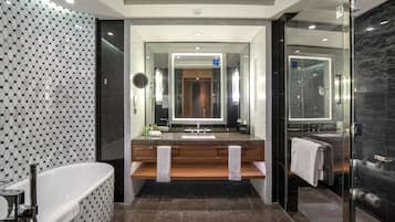 Un baño moderno con una bañera independiente, un tocador con espejo y una zona de ducha con mampara de cristal.