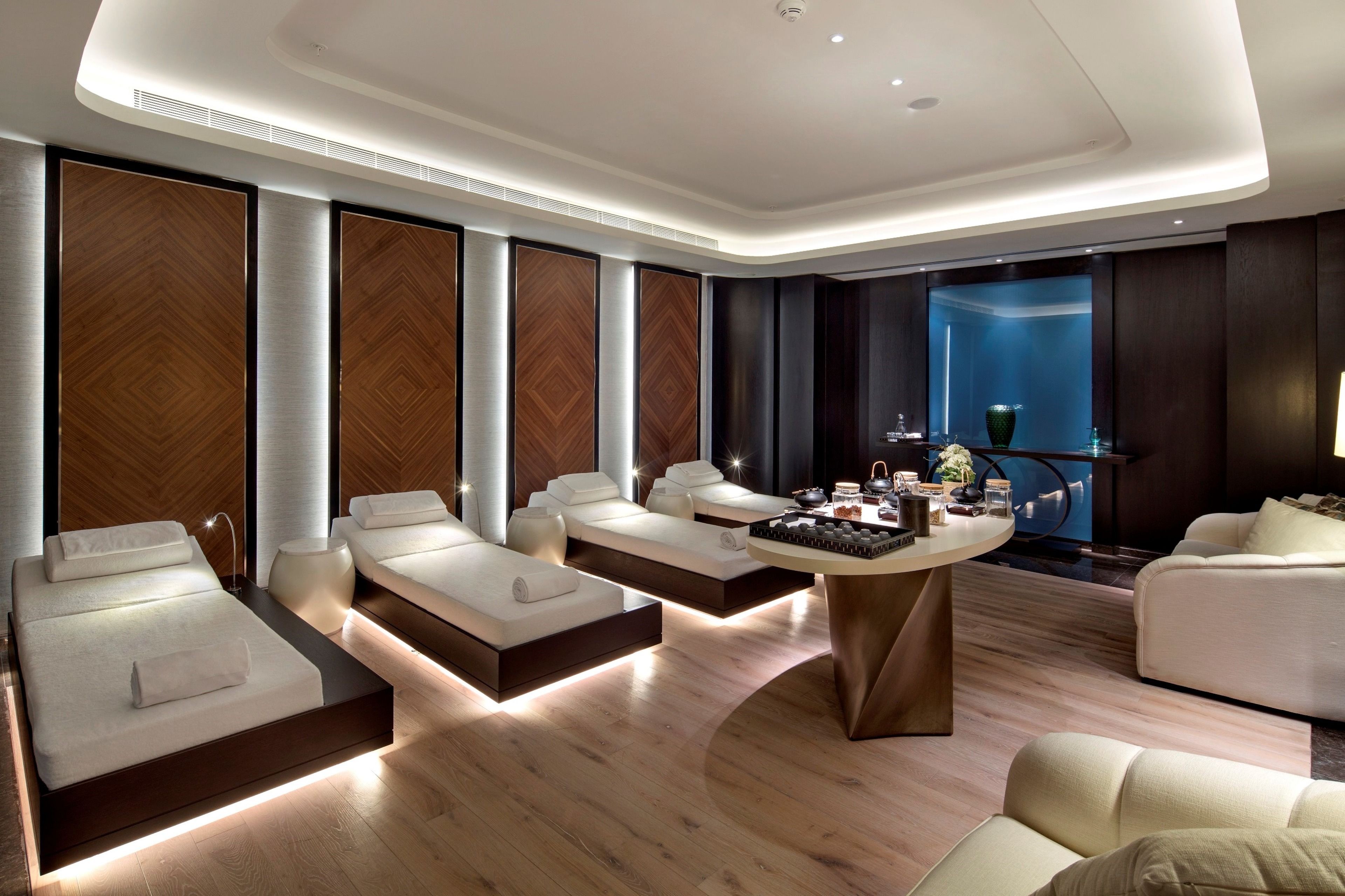 Um spa moderno com várias áreas de estar, uma mesa central com comodidades e uma janela grande com vista.