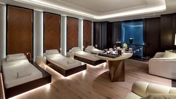 Um spa moderno com várias áreas de estar, uma mesa central com comodidades e uma janela grande com vista.